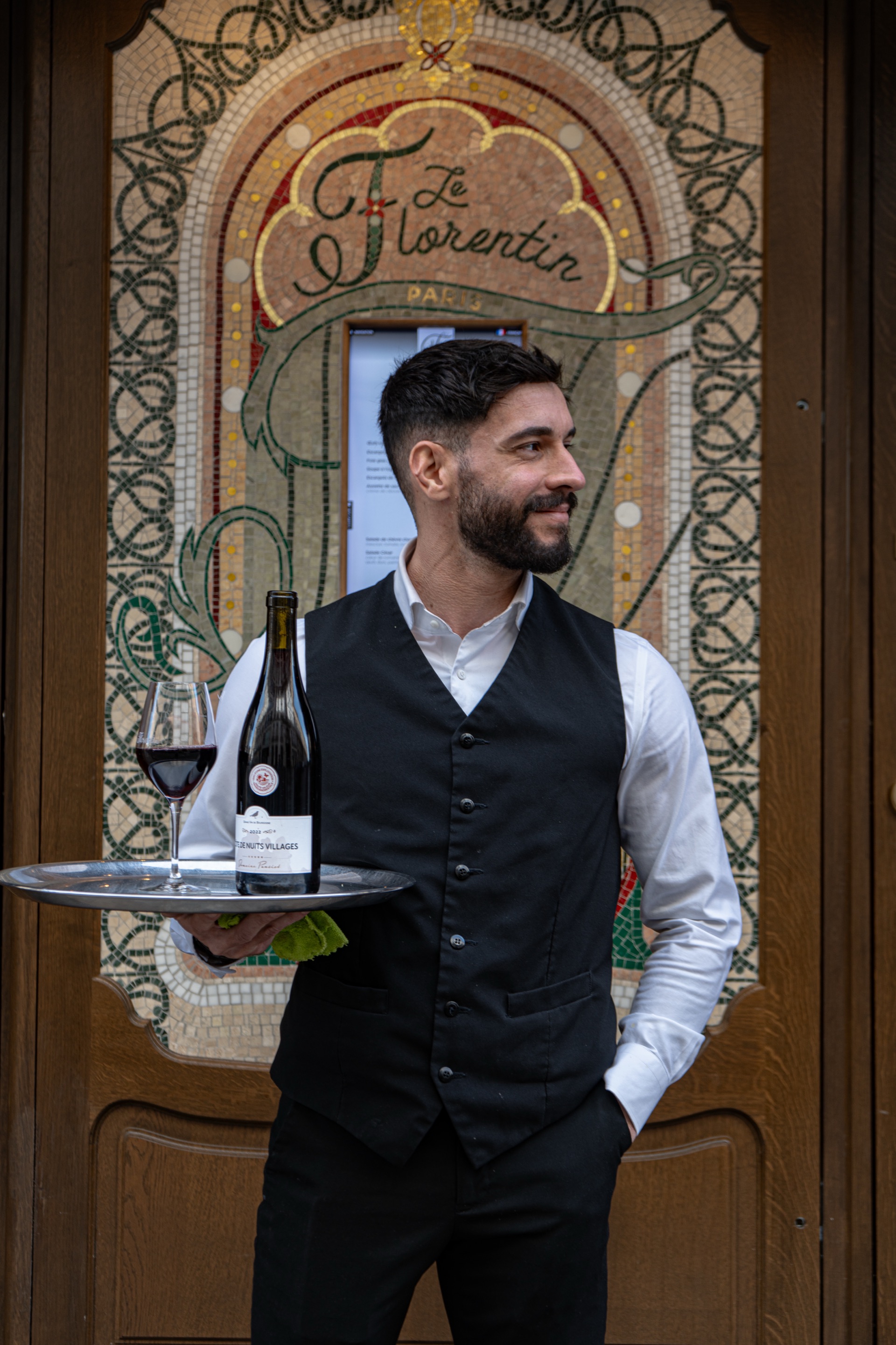 服务员手持酒盘站在Le Florentin马赛克门前