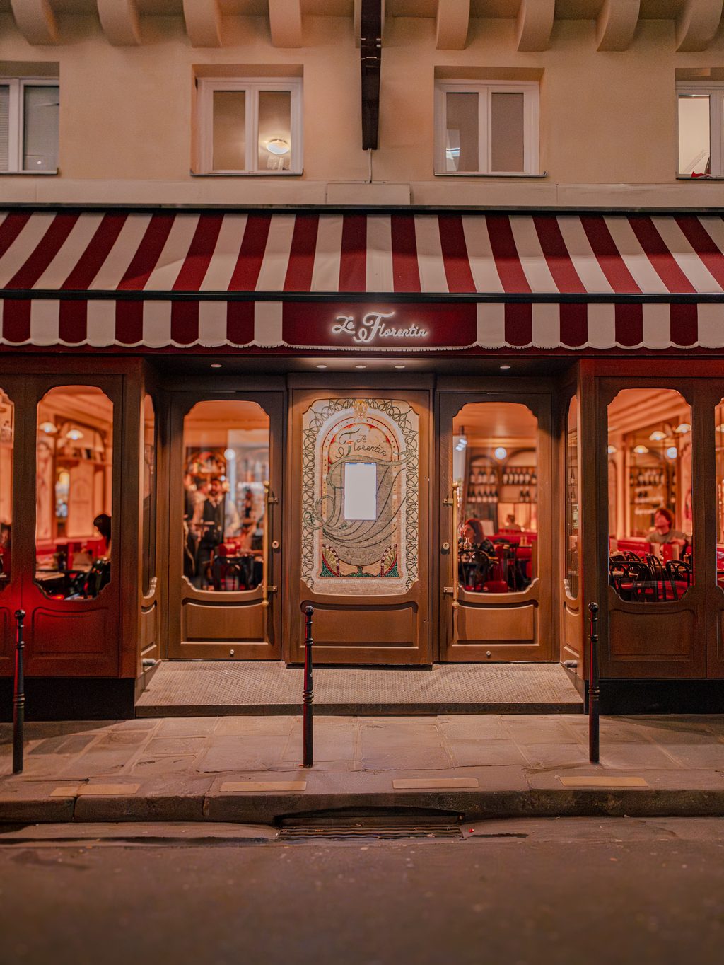 Façade du restaurant Le Florentin de nuit — marquise rayée, porte mosaïque Art Nouveau, intérieur chaleureux